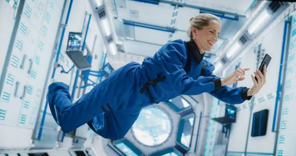 istock Astronaut Floating in Zero Gravity on Board a Spacecraft. Caucasian Female Having a Video Call with a Family or Friends From Planet Earth. Engineer Using Smartphone in Space Inside Orbiting Spaceship 2156520671