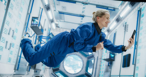 istock Astronaut Floating in Zero Gravity on Board a Spacecraft. Caucasian Female Having a Video Call with a Family or Friends From Earth. Engineer Using Smartphone in Space Inside an Orbiting Spaceship 2156520693