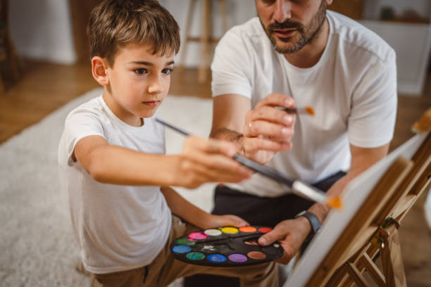 istock Father and son paint together at home learn and have fun bonding time 2156521376