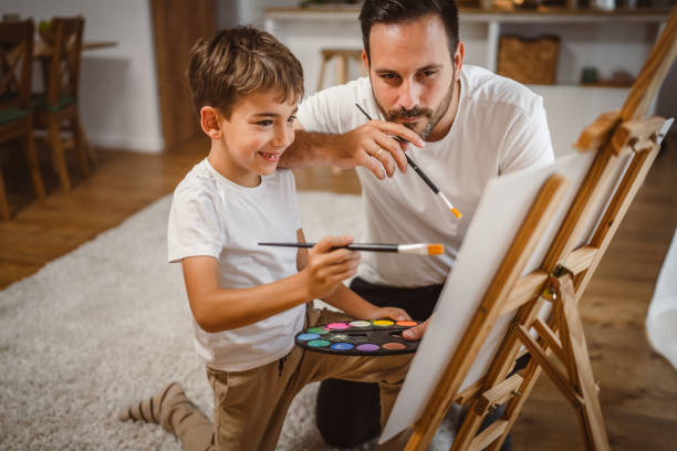 istock Father and son paint together at home learn and have fun bonding time 2156521897