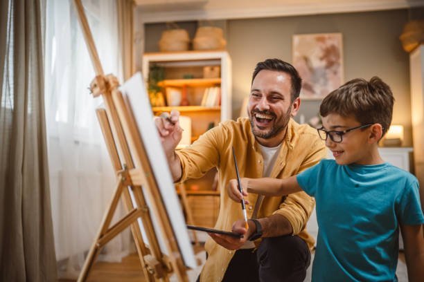 istock Father teach mentor son to create art at home on easel with brush 2156522092