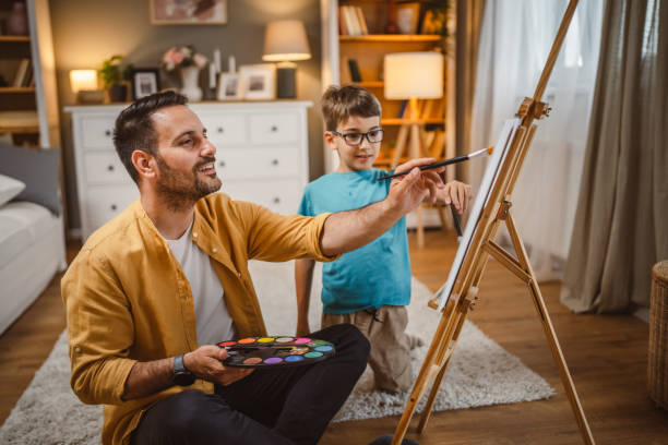istock Father teach mentor son to create art at home on easel with brush 2156522917
