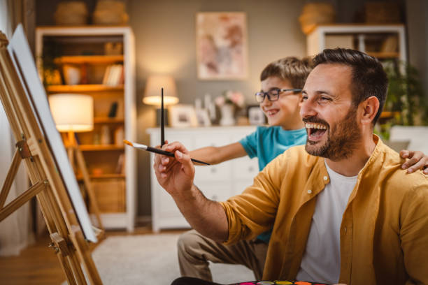 istock Father teach mentor son to create art at home on easel with brush 2156522918