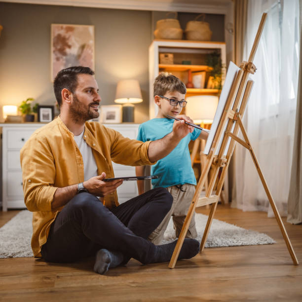 istock Father teach mentor son to create art at home on easel with brush 2156522982