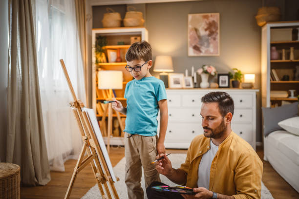 istock Father teach mentor son to create art at home on easel with brush 2156523169