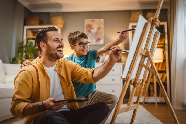 Father teach mentor son to create art at home on easel with brush