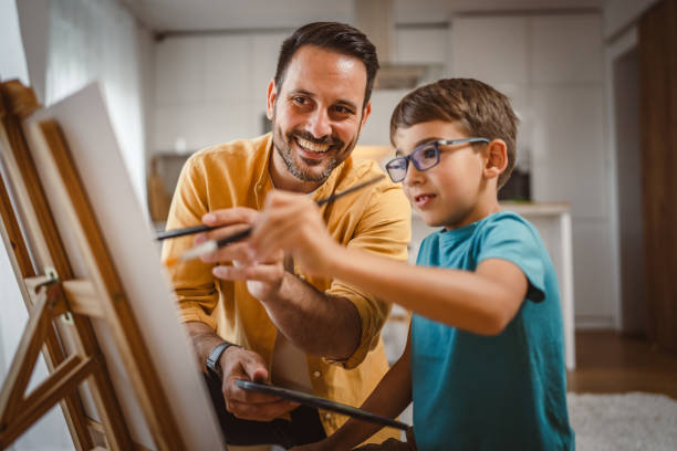 istock Father and son paint at home mentor artist help teach to create art 2156523320