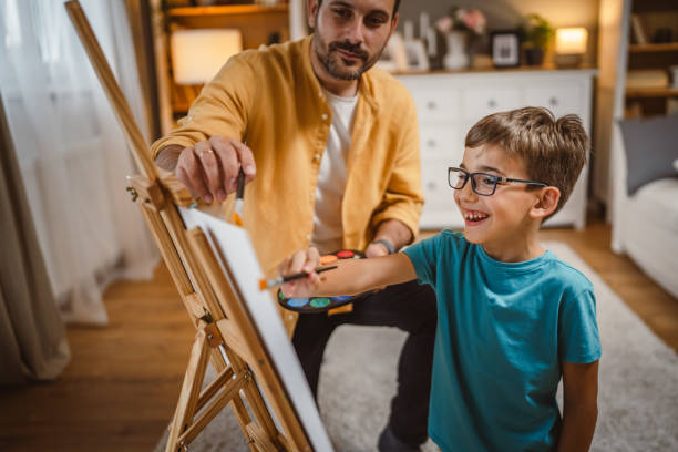 istock Father teach mentor son to create art at home on easel with brush 2156523515