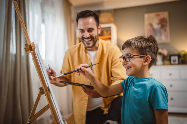 istock Father teach mentor son to create art at home on easel with brush 2156523596