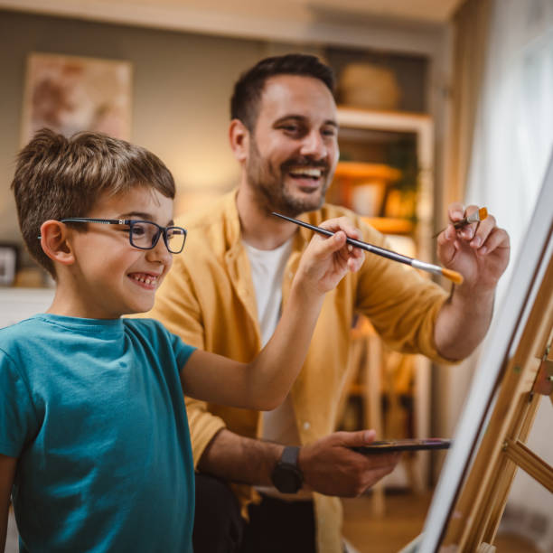 istock Father teach mentor son to create art at home on easel with brush 2156523708