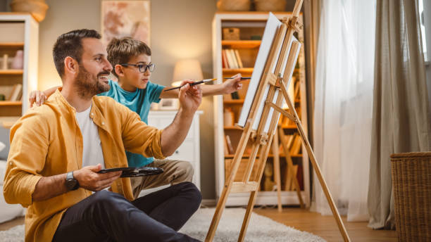 istock Father teach mentor son to create art at home on easel with brush 2156523807