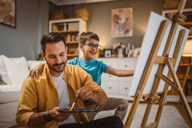 istock Father teach mentor son to create art at home on easel with brush 2156523872