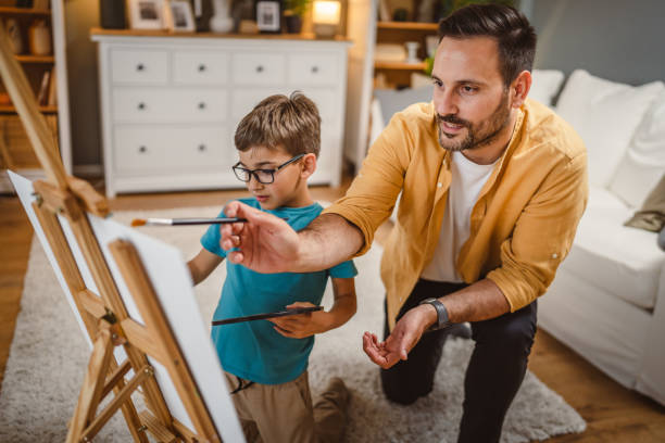 istock Father teach mentor son to create art at home on easel with brush 2156523978
