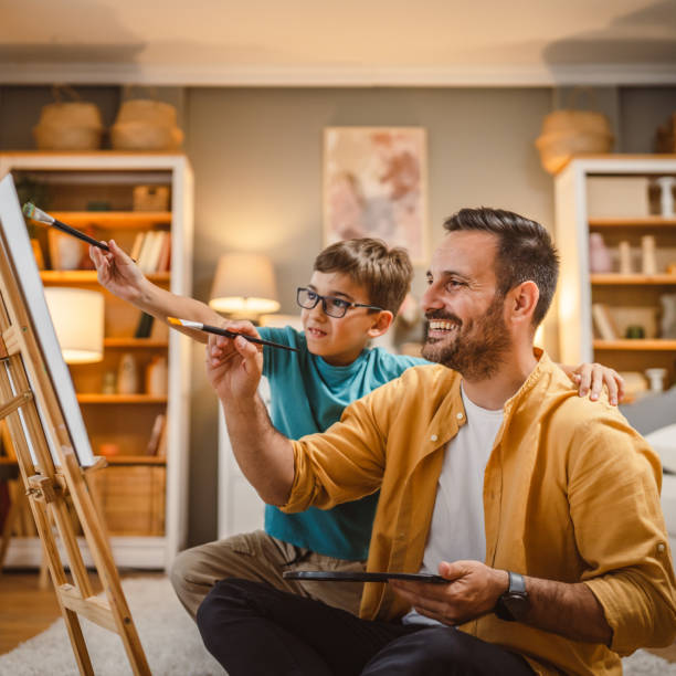 istock Father teach mentor son to create art at home on easel with brush 2156523979