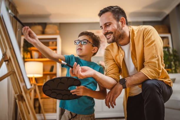 istock Son show his father what he learn to paint on easel with brush 2156523986