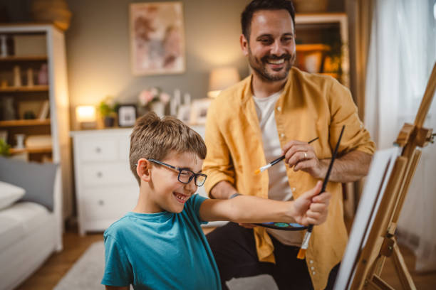 istock Son show his father what he learn to paint on easel with brush 2156523989
