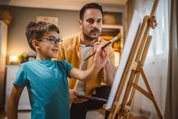 istock Father teach mentor son to create art at home on easel with brush 2156524032