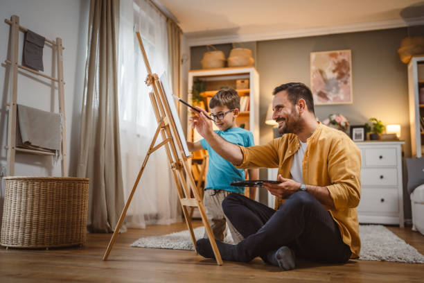 istock Father teach mentor son to create art at home on easel with brush 2156524072