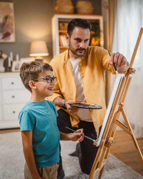 istock Father teach mentor son to create art at home on easel with brush 2156524083