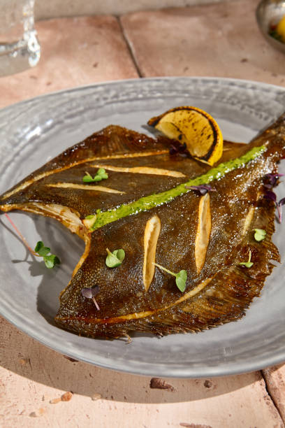 istock Golden Crispy Flounder with Lemon Slice in Natural Sunlight on Beige Table 2156526933