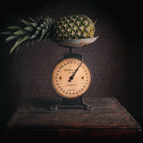 Pineapple on an antique scale Still life image of a pineapple being weighed on an antique scale. vintage kitchen scale with fruit stock pictures, royalty-free photos & images