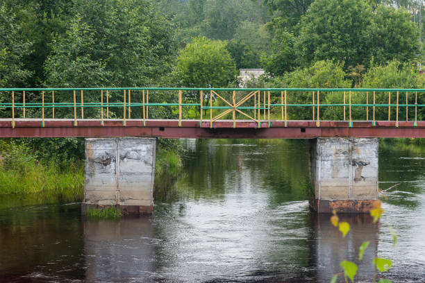 a pedestrian iron bridge on concrete pillars across the river. travel and tourism