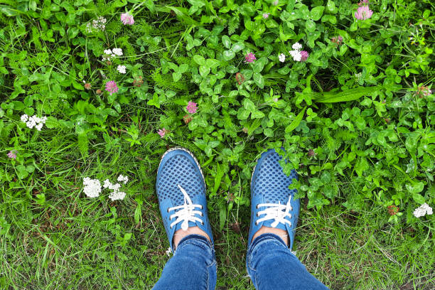 View from above on feet in blue leather summer shoes and jeans. Human and nature. Earth Day. Vacation concept, walking outdoors