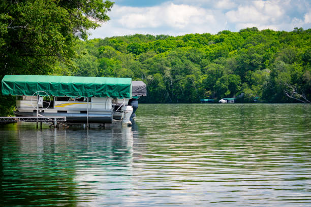 A wooden dock gently extends into the serene waters of a tranquil lake, nestled amidst the rustic charm of Ontario's cottage country in Canada.