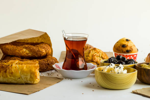 Close-up taken of Traditional Turkish patisserie bakery products various with sesame bagel,simit and Turkish Tea on white with kraft paper bags.
