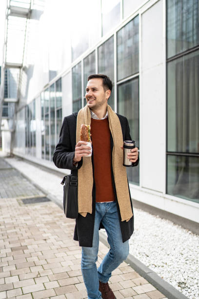 istock Businessman eating sandwich and drinking coffee 2156548934