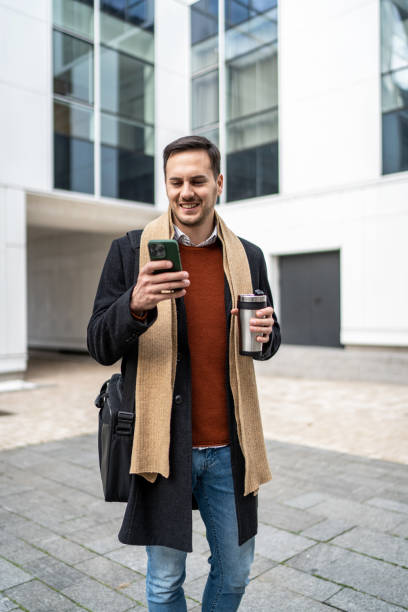 istock Young businessman on the move using his smartphone and drinking takeaway coffee 2156550702
