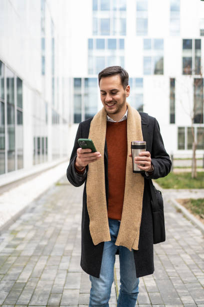 istock Young businessman on the move using his smartphone and drinking takeaway coffee 2156551335