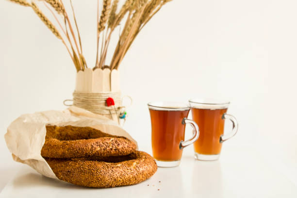 Close-up taken of Traditional Turkish sesame bagel, simit, in paper bag with traditional Turkish Tea and cheese on white background