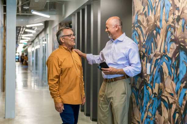 istock Two men chatting in corporate office holding a portable solar charger 2156555828