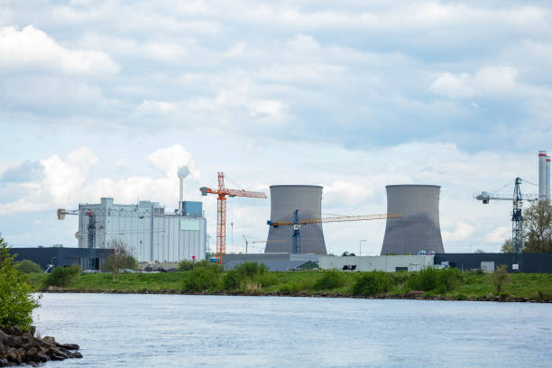 istock Power plant with cooling tower complex by the river and cranes 2156556278