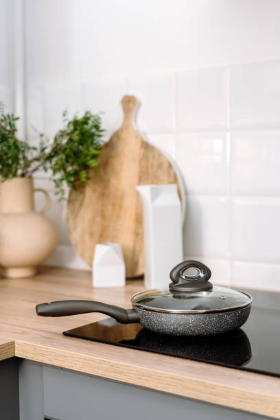 istock Selective focus on frying pan with lid on modern induction stove at kitchen 2156557342