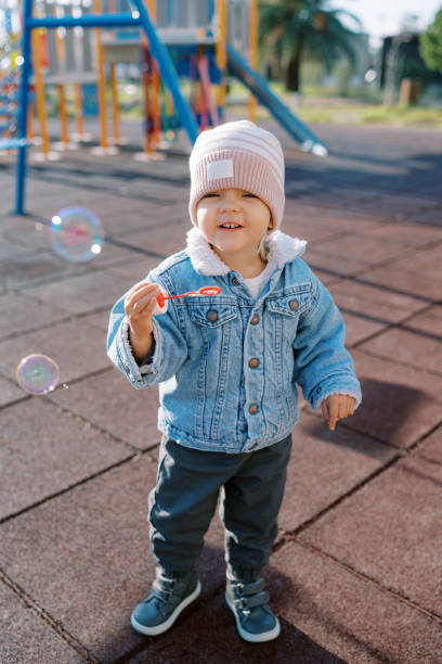 istock Little smiling girl blowing soap bubbles on the playground 2156557778