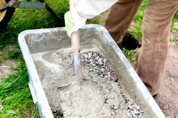 istock worker man mixing, stirring cement slurry, concrete rubble mortar with shovel in big bowl, reservoir, trough, bucket. Preparing for building process, renovation, laying foundation 2156559234