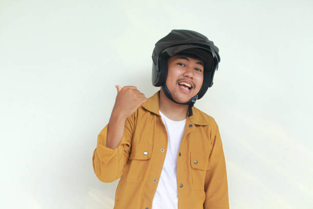 istock Young Asian man happy expression and pointing while wearing a motorcycle helmet. 2156563244