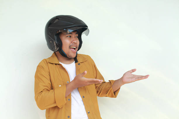 istock Young Asian man happy expression and pointing while wearing a motorcycle helmet. 2156563246