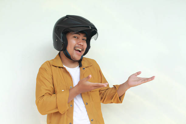 istock Young Asian man happy expression and pointing while wearing a motorcycle helmet. 2156563249