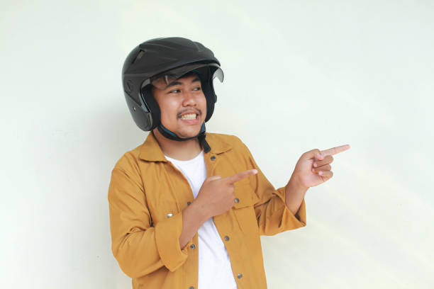 istock Young Asian man happy expression and pointing while wearing a motorcycle helmet. 2156563250