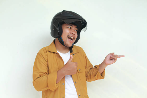 istock Young Asian man happy expression and pointing while wearing a motorcycle helmet. 2156563252