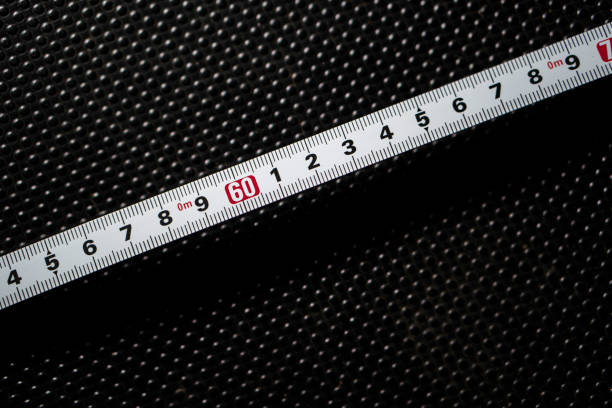 Close-up of a measuring tape showing the number 60 against a dark textured background.
