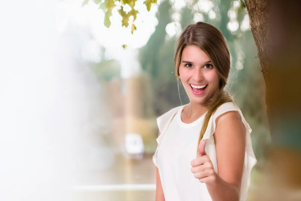Facial expressions theme: Portrait of happy and smiling cute Hispanic young woman showing thumb up with copy space available