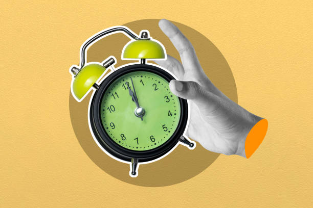istock Hand holding vintage alarm clock on yellow background 2156579594