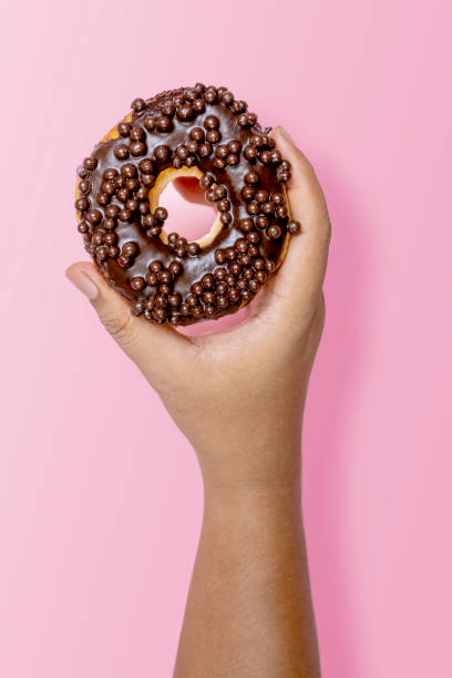 istock A human hand holding a delicious donut with a chocolate sprinkle decoration 2156581311