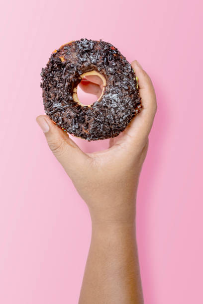 istock A human hand holding a delicious donut with a chocolate sprinkle decoration 2156581330