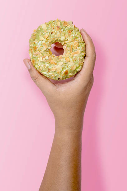 istock Hand holding a pistachio donut on a pink background 2156581543