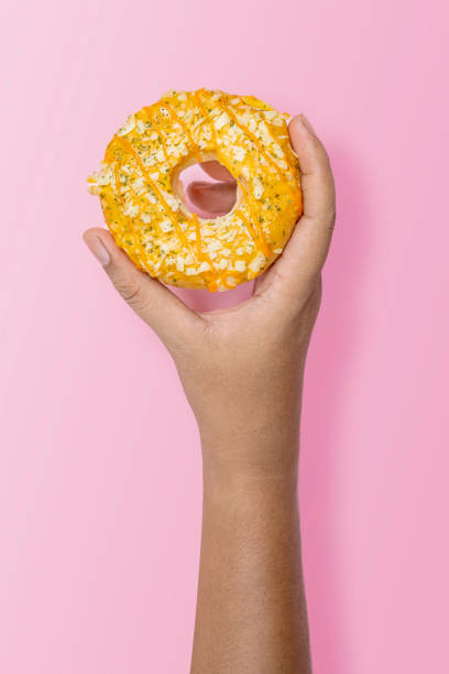 istock Hand holding a sprinkled donut on pink background 2156581560